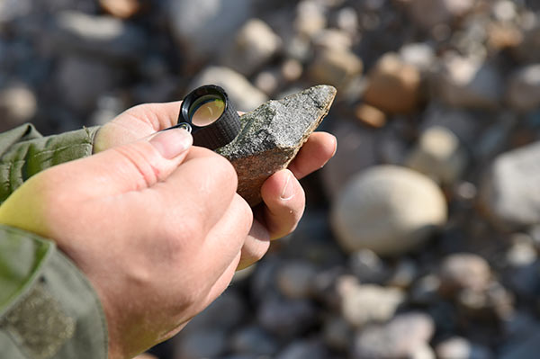 Geologi tutkimassa kivinäytettä.